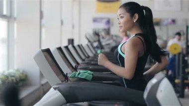 Spor salonunda treadmill çalıştıran çekici Asyalı kız. Sol profil yüz vurdu