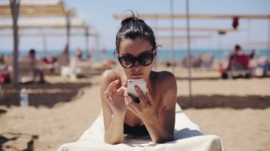 Çekici kadın rahatlatıcı ve app smartphone kullanarak güneş gözlüğü