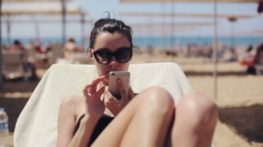 Çekici kadın rahatlatıcı ve app smartphone kullanarak güneş gözlüğü