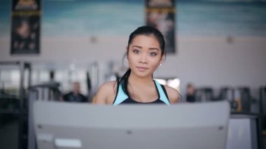 Spor salonunda treadmill çalıştıran çekici Asyalı kız. Tam yüz portre