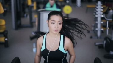 Kulaklık ile spor salonunda treadmill çalıştıran çekici Asyalı kız. Tam yüz portre