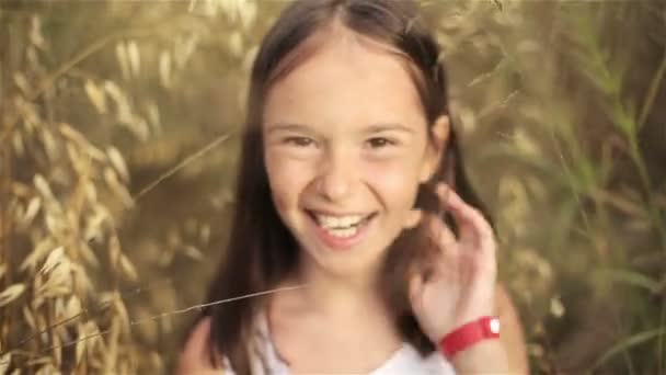 Retrato de uma menina em um campo de grama alta ao pôr do sol — Vídeo de Stock