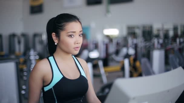 Attrayant asiatique fille courir sur le tapis roulant dans la salle de gym. Portrait droit 3 / 4 — Video