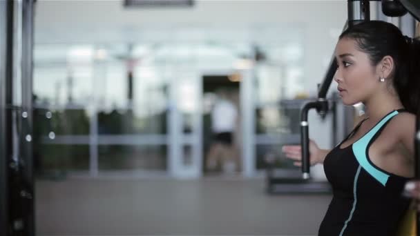 Joven atractiva mujer asiática en el gimnasio. Filmación por control deslizante (dolly) de izquierda a derecha — Vídeos de Stock