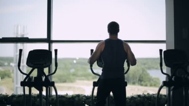 Süzgeç makinede egzersiz spor salonunda yakışıklı adam silüeti. Sağa sola ateş dolly