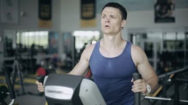 Süzgeç makinede egzersiz spor salonunda yakışıklı adam. 3/4 yüz portre yaptı