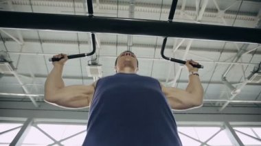 Erkek vücut geliştirmeci yukarı çekerek bir spor salonunda, yakın çekim