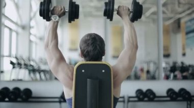 Adam vücut geliştirmeci spor salonunda egzersiz dumbbells ile yürütmek. Arka beden görüntüleri
