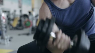 Adam vücut geliştirmeci spor salonunda egzersiz dumbbells ile yürütmek. Yüzü olmayan