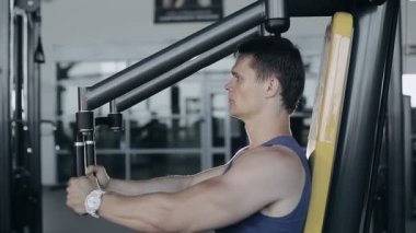 Kaslı vücut geliştirmeci göğüs kasları için spor salonunda egzersiz egzersiz yapıyor. Tam yüz vurdu