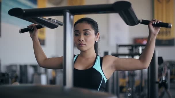 Asiatisk kvinna gör övningar på power träning apparater i gymmet — Stockvideo