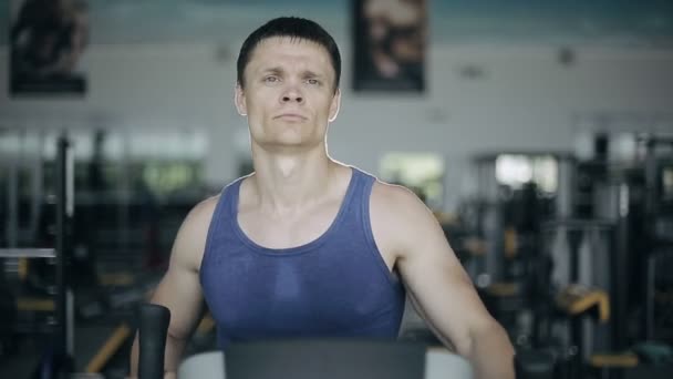 Hombre guapo en el gimnasio haciendo ejercicio en la máquina de colar. Cara llena — Vídeos de Stock