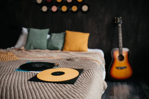 Yellow and black vinyl records on a bed in bedroom decorated with vintage vinyl records.