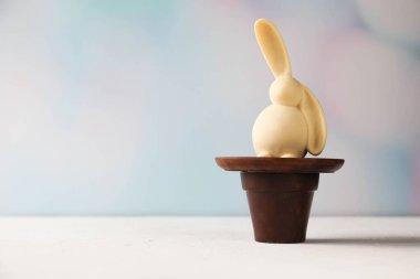 Modern bir Paskalya tavşanı çikolata tenceresi ve çikolata tabağı üzerinde otururken çekilmiş yaratıcı bir fotoğraf.