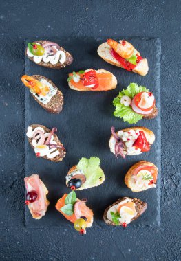 İspanyol deniz mahsullü tapas sandviçleri - karides, ahtapot, kalamar, somon, gorgonzola peyniri, krem peynir, otlar, üzümler ve yaban mersinli yeşil zeytinler - üst görünüm ve kopyalama alanı