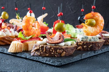 Akdeniz yemeği kavramı - karides, ahtapot, mürekkep balığı, yeşil zeytin, somon, gorgonzola peyniri, üzüm, krem peynir, kırmızı biber, yaban mersininden oluşan İspanyol tapas sandviçi