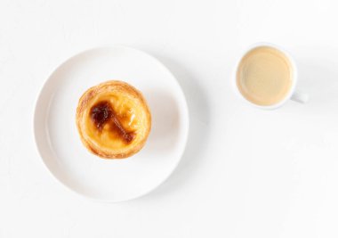 Pastel de nata - Portekiz 'den geleneksel kremalı pasta ve bir fincan kahve - Sabah kahvaltısı tatlı konsepti - üst manzara, beyaz arka plan