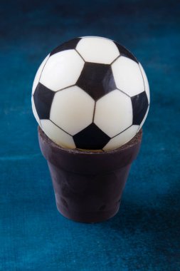 Masanın üzerindeki çikolata kabında siyah beyaz top şeklinde bir pasta. Tatlıya ve Avrupa futbolu hayranına bir hediye olarak.