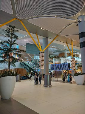 İstanbul, Türkiye - 12 Aralık 2019: İstanbul 'un ana havaalanı IST' si Yeni Yıl oyuncaklarıyla süslendi. Büyük salonda, insanlar havaalanında yürür. Dikey.