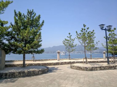 MIYAJIMA, JAPONYA - 10 Nisan 2018: Miyajima Adası deniz manzaralı gezinti alanı. Hiroşima şehrine giden feribotun görüntüsü..