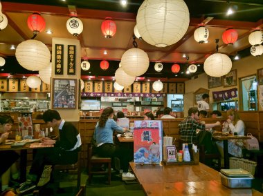 OSAKA, JAPAN - APRIL 4, 2018: The atmosphere of a traditional Japanese style restaurant in Osaka. The room is brightly decorated with lanterns, people eat and communicate.