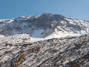 Mutnovsky yanardağına tırmanan turistler. Mutnovsky yanardağının karla kaplı dağlarını mavi gökyüzünün arka planında görüyoruz. Kamçatka Yarımadası, Rusya.