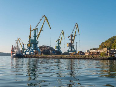 Petropavlovsk-Kamchatsky Avacha Körfezi 'ndeki liman. Rıhtımda mavi gökyüzüne karşı duran uzun vinçler. Kamçatka Yarımadası, Rusya.