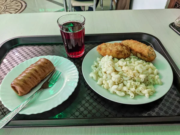 Rus kantininde, az paraya lezzetli bir set menüsü sipariş edebilirsiniz. Pirzolalı makarna, hamur sosisi ve komposto plastik kahverengi tepside servis edilir..
