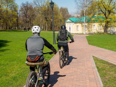 Moskova, Rusya - 1 Mayıs 2021 Kolomenskoye Parkı, Moskova 'da güneşli bir bahar günü. Aileler büyük parklarda bisikletlerine binerler ve bir Mayıs günü güzel havanın tadını çıkarırlar..