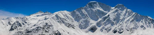 チェゴからのコーカサス山脈のパノラマビュー 高さ3050メートル カバルディノ バルカリア ロシア 青空に向かって雪をかぶった山の写真 — ストック写真
