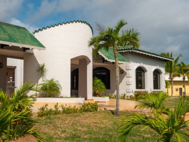 Restoranın İtalyan usulü Tryp Cayo Coco otelinde inşa edilmesi. Tropikal bitkiler yeşil çatılı ve büyük pencereli beyaz bir binanın yanına dikilir. Cayo Adası Coco, Küba.