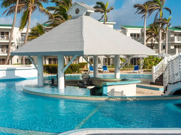 Bar area in the middle of the pool for tourists to relax in the Cuban hotel. Guests can sit on stone chairs outside the bar and hide under a roof from the sun. Island Cayo Coco, Cuba.