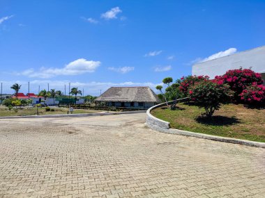 Otel Tryp Cayo Coco bölgesinin ana girişinden güzel bir manzara. Parlak pembe çiçekler ve yüksek palmiyeler ana binanın dışında mavi bir gökyüzüne karşı büyür..