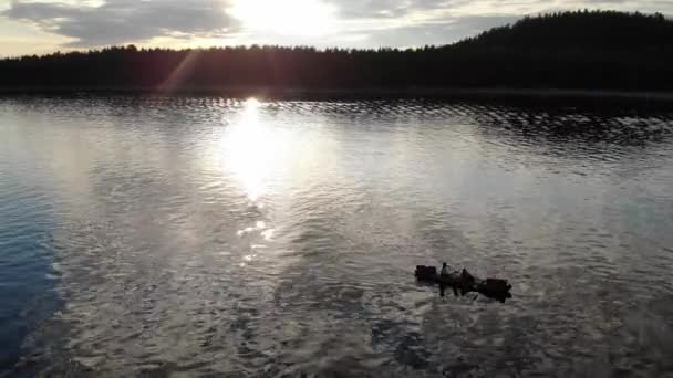 皮艇和两个人在湖里。夏日的落日映照在水面上. — 图库视频影像