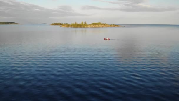 Кая з двома людьми в озері. захід сонця влітку. уздовж берега кам'яний острів — стокове відео