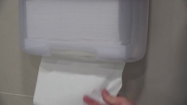 Die Hand reißt Einwegpapiertücher aus dem Spender. öffentliches Toilettenbad — Stockvideo