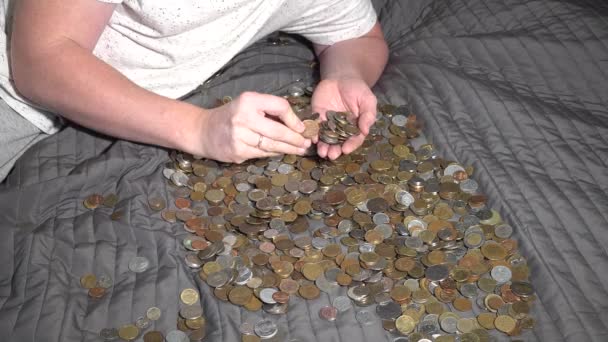 Eine Person wählt aus einem Haufen von Münzen aus verschiedenen Ländern. Lügt die Couch — Stockvideo