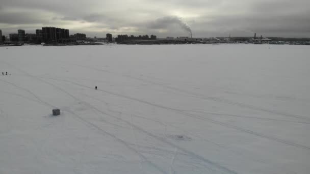 Fishermen fishing on ice in winter near the city. High-rise buildings background — Stock Video