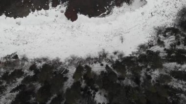 Büyük taşları ve ağaçlı ormanı olan karlı kış kıyıları. Göl Koyu ya da Deniz. 