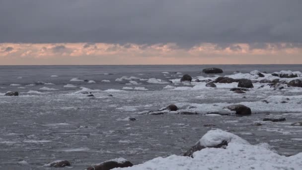 Bevroren stenen met ijs. ijsglazuur Golven in een baai meer of zee. bij de kust. Zonsondergang — Stockvideo