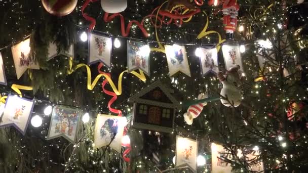 Decorado gran árbol de Navidad con luz de fondo en la calle. Banderas juguetes y bombillas — Vídeo de stock