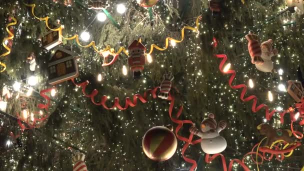 Decorado gran árbol de Navidad con luz de fondo en la calle. Banderas juguetes y bombillas — Vídeo de stock