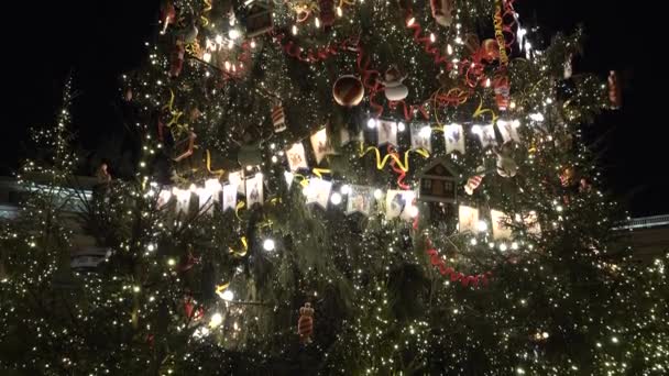 Versierde grote kerstboom met achtergrondverlichting op straat. Vlaggen speelgoed en bollen — Stockvideo