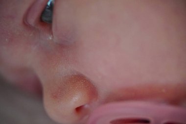 Yeni doğmuş bebek suratı. Aç gözlerini. Pembe emzik ile. Makro görünümü kapat.