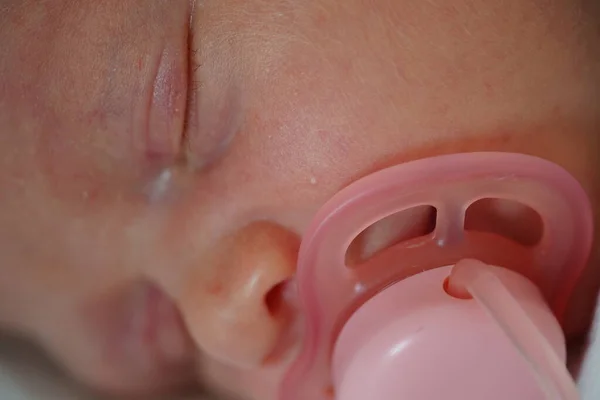 Cara de bebé recém-nascido. Fecha os olhos. Com chupeta rosa. close up vista macro close-up — Fotografia de Stock