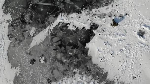 Самотній рибалка льодовик. снігові дюни. Тріснутий лід з отворами. Вид з повітря — стокове відео