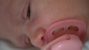 Yeni doğmuş bebek suratı. Aç gözlerini. Pembe emzik ile. Makro görünümü kapat.