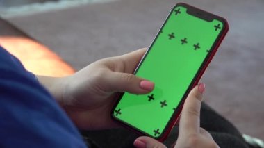 Yatay ekran telefon yeşil krom anahtarı. Adam kanepede oturuyor.