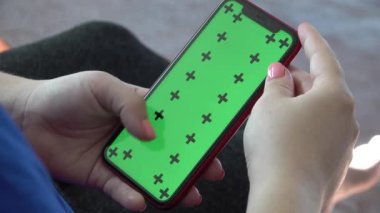 Dikey ekran telefon yeşil krom anahtarı. Adam kanepede oturuyor.