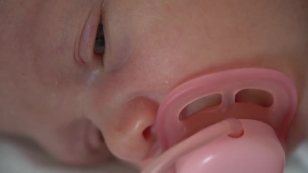 Faccia da neonato. Apri gli occhi. Con ciuccio rosa. primo piano macro vista da vicino — Video Stock